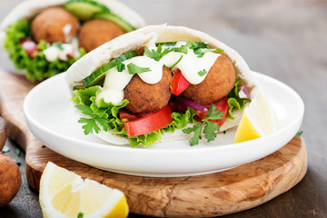 Falafel and fresh vegetables in pita bread on wooden table.