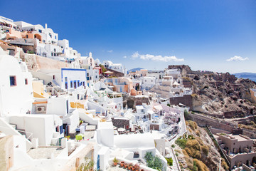 Fototapeta premium beautiful Oia town on Santorini island, Greece. Traditional white architecture and greek orthodox churches with blue domes over the Caldera, Aegean sea. Scenic travel background