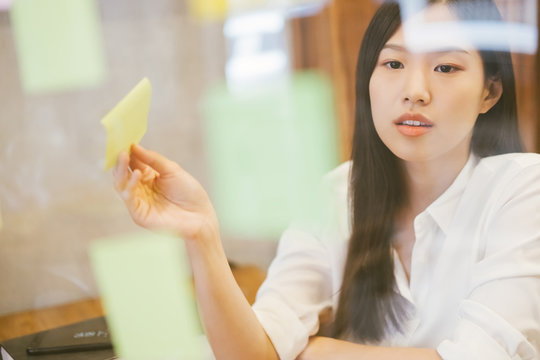 Young creative Asian woman working in modern office. use post it for meeting