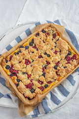 crumble cake in a baking form and pieces of the cake on a table