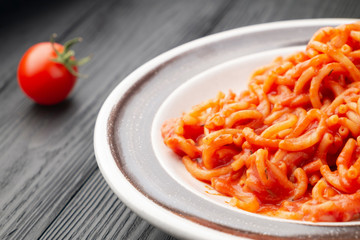 Vermicelli in tomato sauce. Nearby are cherry tomatoes.