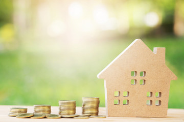 money coins stacked on each other in different positions and home in brown recycled paper model on...