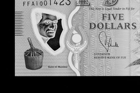Five Fijian dollars banknote on a black background close up. Black and white