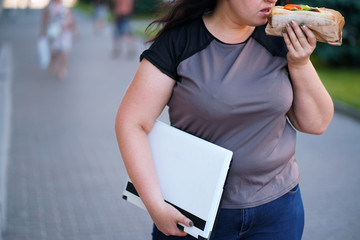 Unhealthy fast food, lunchtime, high-calorie snack, sedentary working, eating on the go. Overweight...