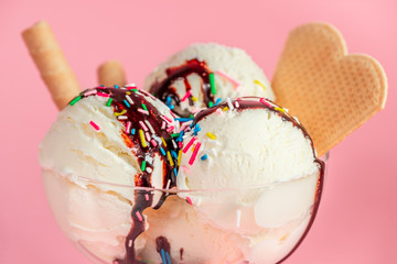 close up of vanilla flavor ice cream in glass bowl with chocolate sauce, strewed sprinkles and...
