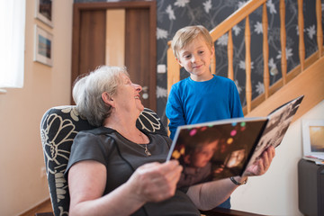 Grandmother and grandson watching photo album with the grandson pictures on the cover