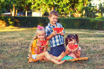 Fototapeta premium Children with watermelon in nature . A group of children on a picnic with a ripe watermelon