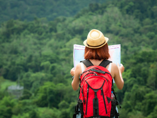 Asia woman traveler hiking with backpack and camera at forest looking map the route go to...