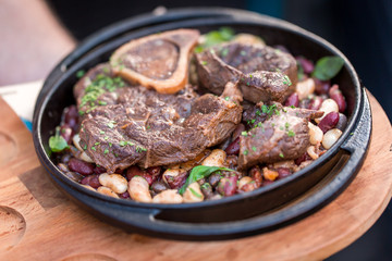 Serving grilled beef steak with beans close-up on a plate on a table.