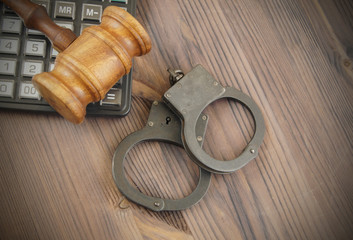 Wooden gavel, calculator and black handcuffs. financial fraud concept