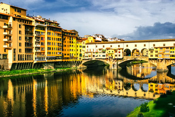 Obraz premium Old bridge Ponte Vecchio with colourful buildings houses and its reflection in the river Arno in Florance, Tuscany, Italy. April 2012