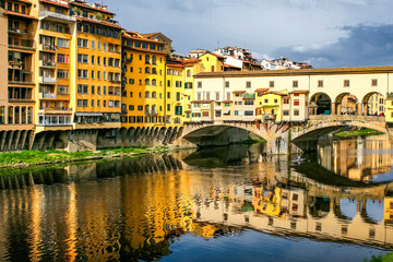 Old bridge Ponte Vecchio with colourful buildings houses and its reflection in the river Arno in Florance, Tuscany, Italy. April 2012