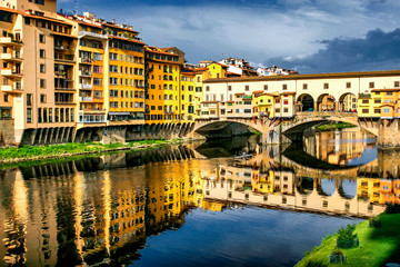 Old bridge Ponte Vecchio with colourful buildings houses and its reflection in the river Arno in Florance, Tuscany, Italy. April 2012