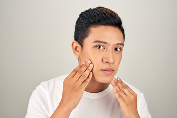 Portrait of shirtless young handsome Asian man checking his face for skin care and beauty concepts