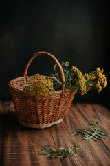 Fototapeta na wymiar Autumn composition with yellow tansy flowers in a wicker basket on a wooden background