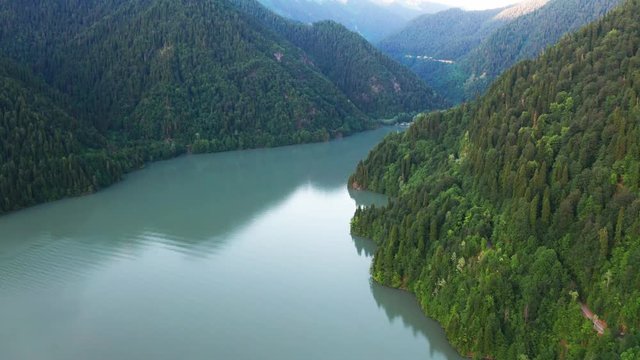 Aerial video shooting. Lake Ritsa, Abkhazia. Highest mountain. Pure mountain water. Tall green trees. Snow-capped mountains. Wildlife. No people