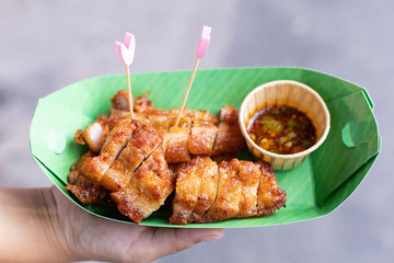 Women's hands holding a box of fried pork.