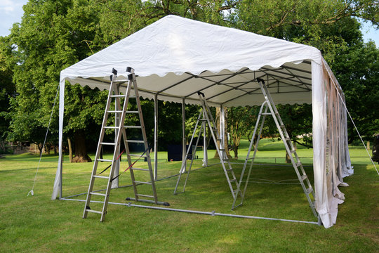 event tent set up  with ladders on the lawn in a park for a summer party or wedding