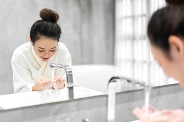 Obraz na płótnie Canvas Beautiful young asian woman washing clean face with water and smiling in front of the mirror in the bathroom.beauty and spa.perfect fresh skin