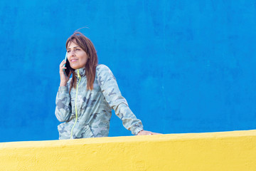 Happy young woman talking on mobile phone at city street lifestyle portrait.