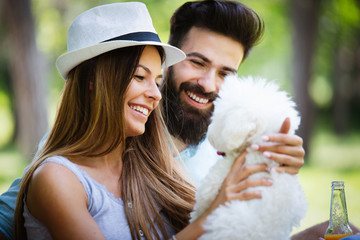 Lifestyle, happy couple resting at a picnic in the park with a dog
