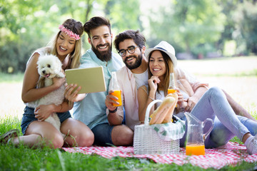Happy friends in the park having picnic on a sunny day.