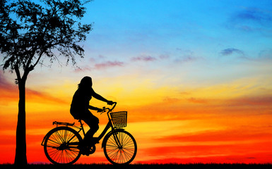 Obraz premium Silhouette man and bike relaxing on blurry sunrise sky background.