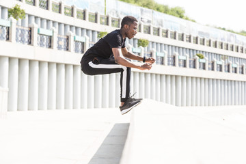 Athletic young afroamerican man running on the promenade. Black Male runner sprinting outdoors. Healthy lifestyle concept.