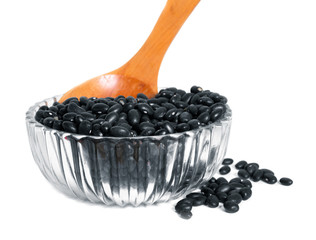 black beans with wooden spoon in clear Glass bowl on white background
