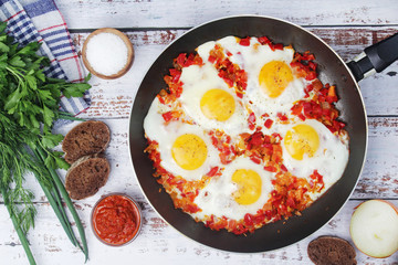 Shakshouka with five cooked eggs on top of tomato sauce in cast iron skillet	