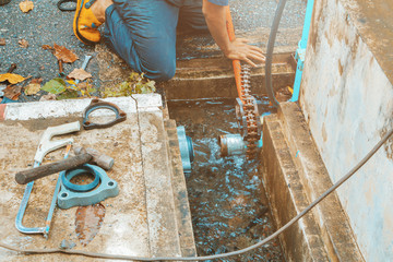 plumber working repair the broken pipe with Adjustable Wrenches or Locking Pliers in hole ditch at...