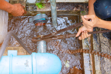 plumber working repair the broken pipe with Adjustable Wrenches or Locking Pliers in hole ditch at...