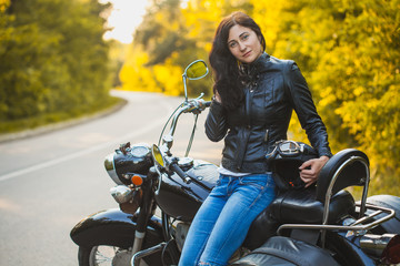 attractive brunette motorcyclist sits on a motorcycle. adventure concept