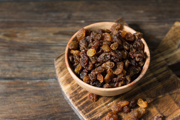 Raisins in a wooden bowl on a wooden table. Rustic style