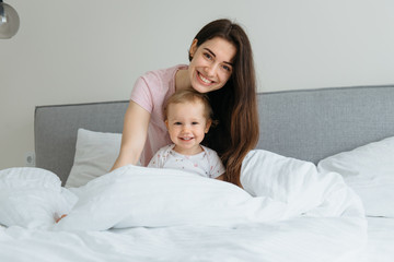 Mother and toddler daughter enjoying time in the bed at home.