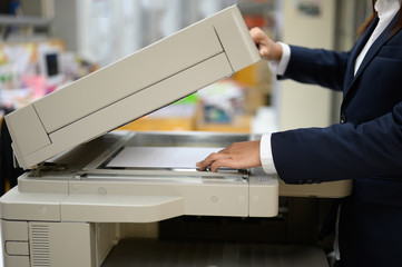 Employees are copying documents with a copy machine at the office.