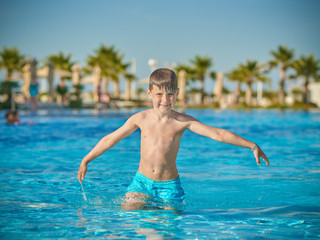 Cute European boy is enjoying his summer vacations. He is having fun in the hotel’s pool.