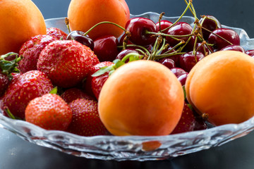 cherries, strawberries, apricots - berries and fruits in a vase. seasonal vitamins