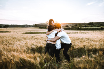 Happy family hugging in the field and smiling. Family in a sunset