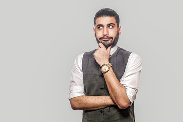 Portrait of thoughtful or confused handsome bearded brunette man in white shirt and waistcoat...