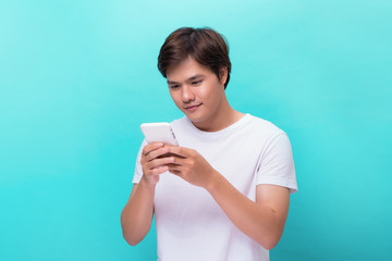 Young man texting message on smart phone isolated on blue background