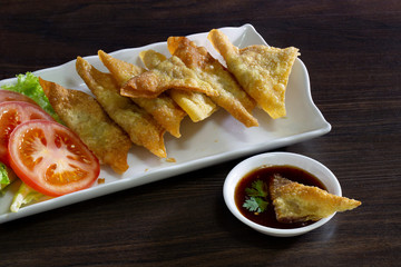 Fried dumplings with sweet sauce Thai food in long white dish  on dark wooden background