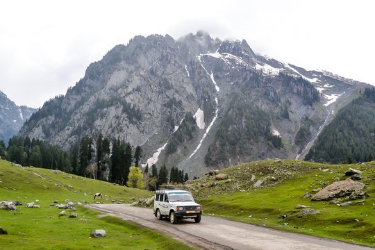 Off-road SUV driving on the rock mountain road in Kashmir Betaab valley (Paradise on Earth) Srinagar, Pahalgam, Jammu and Kashmir, India. Snow frozen Himalayas glacier mountain at a distance.