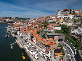 Fototapeta na wymiar Porto, Portugal, may 2019: View over Porto old town with colorful buildings and red roofs. Promenadein Cais de Ribeira along Duoro river on a sunny day.