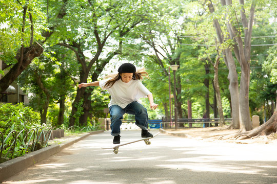 緑道でスケートボードを楽しむ若い女性