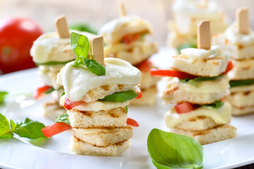Überbackene Caprese-Häppchen: Spießchen mit gegrilltem Bruschettabrot mit Mozzarella, Tomaten und Basilikum –Warm appetizers with buffalo cheese, tomatoes and basil on wooden skewers 