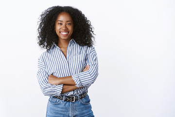 Friendly cheerful attractive african american curly-haired young 25s woman consultant woking talking coworkers smiling pleasant having fun enjoying relaxing company mood, standing hands crossed chest - 274550875