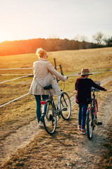 Mother and daughter with bicycles on countryside.