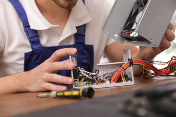 Male technician repairing power supply unit at table, closeup