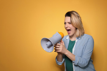 Portrait of emotional woman using megaphone on color background. Space for text